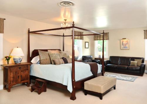 a bedroom with a four poster bed and a couch at 1795 Acorn Inn Bed and Breakfast in Canandaigua