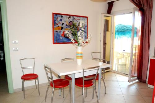 a dining room with a table with chairs and a vase with flowers at La Baia Di Ulisse in Venetico
