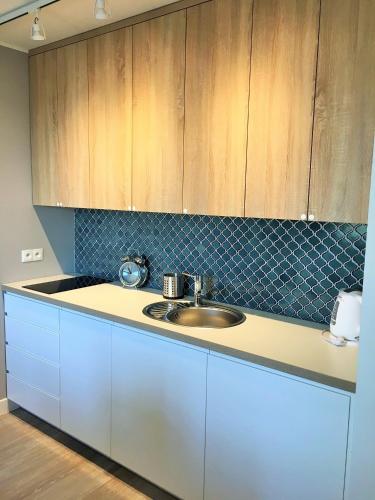 a kitchen with a sink and wooden cabinets at Apartamenty Rewa in Rewa