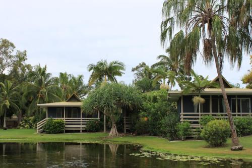 a house by the water with palm trees at Sanctuary Lakes Fauna Retreat in Hervey Bay