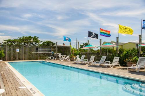 a pool with chairs and umbrellas and flags at First Colony Inn in Nags Head