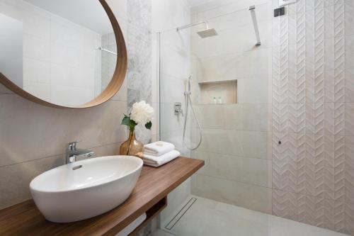 a white bathroom with a sink and a mirror at Hotel Delfin in Rovinj