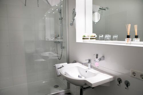 a white bathroom with a sink and a shower at Appartements am Binnenhafen in Helgoland
