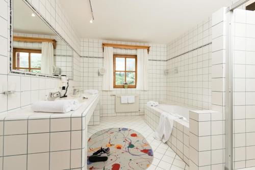 a white tiled bathroom with a tub and a sink at Ansitz Wirtsgut - Familienappartements in den Bergen in Leogang