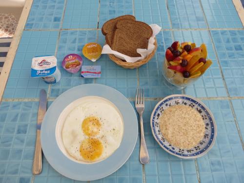 a table with a plate of eggs and a bowl of fruit at El Primo Hotel Dahab in Dahab