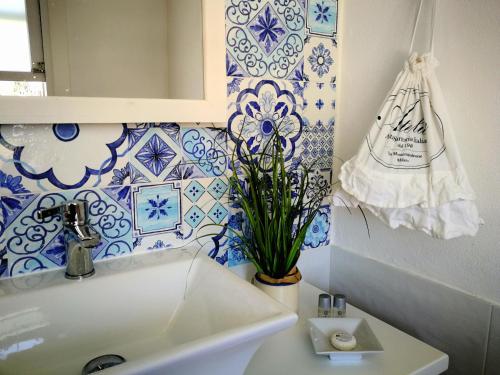 La salle de bains est pourvue d'un lavabo et de carrelage bleu et blanc. dans l'établissement La Casa di Nina, à La Maddalena