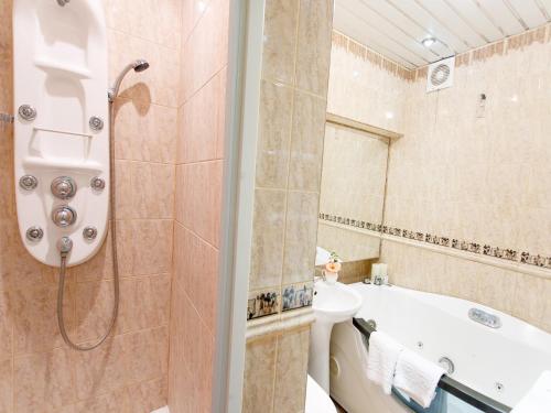 a bathroom with a tub and a shower and a sink at Studio De Luxe with Jacuzzi in Sumy