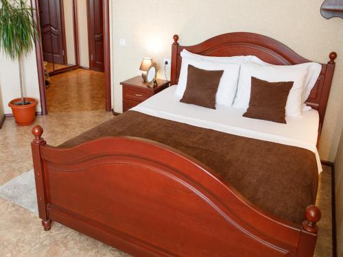 a bedroom with a large wooden bed with pillows at Studio De Luxe with Jacuzzi in Sumy