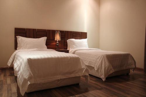 a bedroom with two beds with white sheets and a lamp at شقق درر رامه للشقق المخدومة 3 in Riyadh