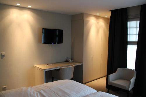 a hotel room with a bed and a desk and a television at Hotel Astel in De Haan