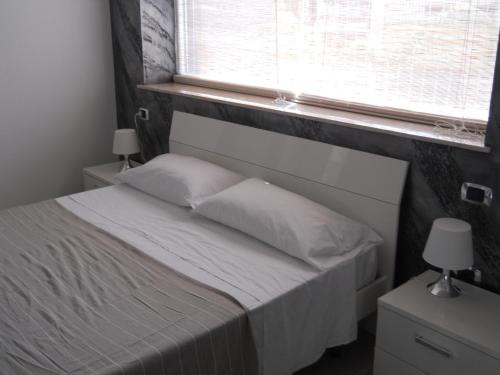 a bedroom with a bed with white sheets and a window at Summer Beach Rooms in Fontane Bianche