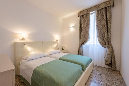 1 dormitorio con 2 camas y ventana en Ca' Dorè, en Venecia