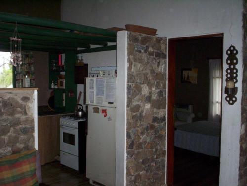a kitchen with a white refrigerator and a stone wall at Verde Niña Casas Serranas in Cortaderas