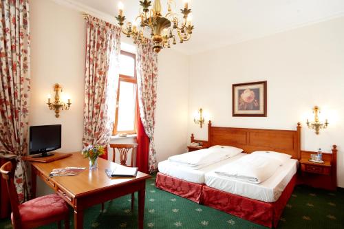 ein Hotelzimmer mit einem Bett, einem Schreibtisch und einem Computer in der Unterkunft Hotel Grünwald in München