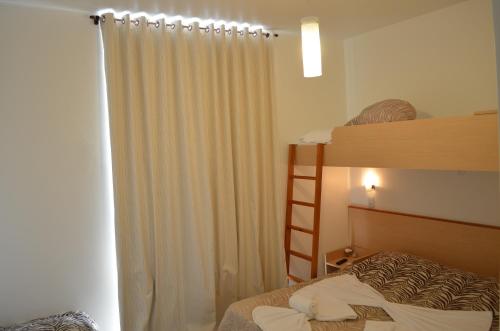 a bedroom with a bunk bed with a ladder and a curtain at Pousada Omnimare in Ubatuba