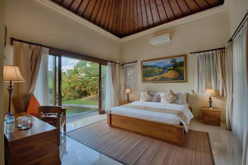 ein Schlafzimmer mit einem Bett und einem großen Fenster in der Unterkunft Kadiga Villas Ubud in Ubud