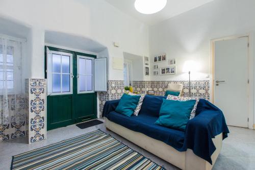a living room with a blue couch and a green door at Santos Neighborhood Apartment in Lisbon