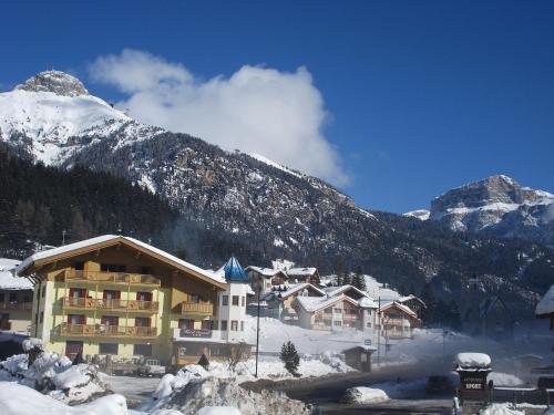 eine Skihütte im Schnee mit einem Berg in der Unterkunft Hotel Ciamol in Mazzin
