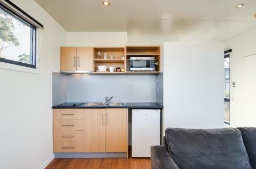 a kitchen with a sink and a couch in a room at Swansea Beach Chalets in Swansea