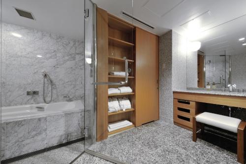 JR Kyushu Station Hotel Kokura في كيتاكيوشو: حمام مع دش وحوض استحمام ومغسلة