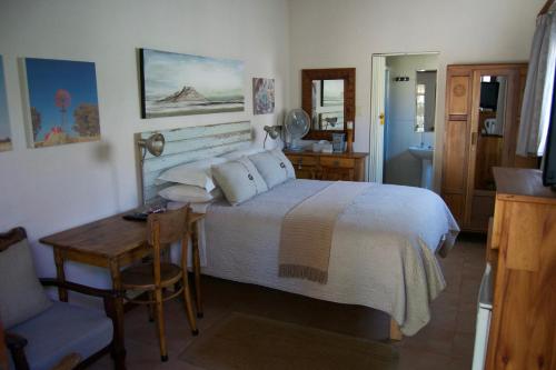 a bedroom with a bed and a table and a chair at LA Guesthouse in Piet Retief