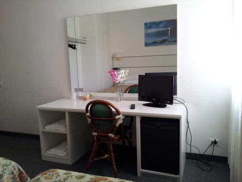 a desk with a computer monitor and a chair at Hotel Post in Bergamo