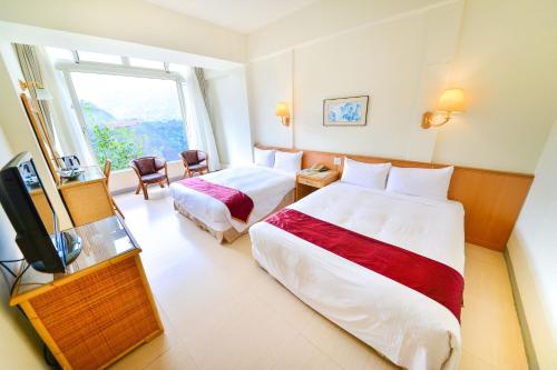 a hotel room with two beds and a television at Dongpo Ti Lun Hotel in Xinyi
