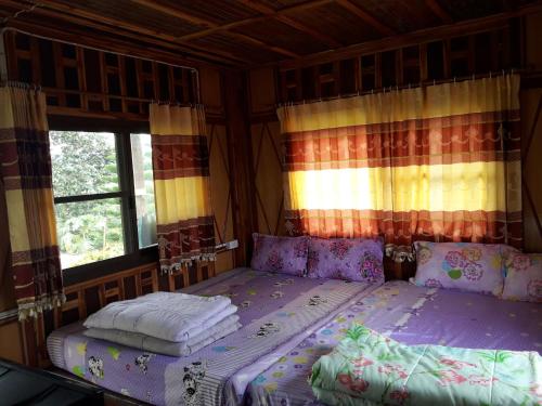 a bedroom with a bed and two windows at Phu Aram Khao Kho Resort in Khao Kho