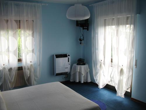 a bedroom with blue walls and white curtains and a bed at Stevano Albergo e Ristorante in Cantalupo Ligure