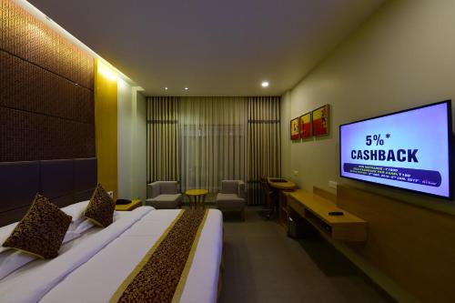 a hotel room with a bed and a flat screen tv at Hotel H - Sandhill Hotels Private Limited in Anand