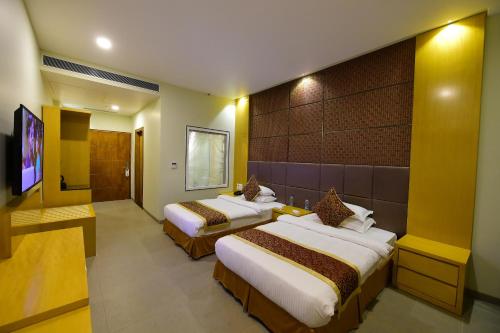 a hotel room with two beds and a flat screen tv at Hotel H - Sandhill Hotels Private Limited in Anand