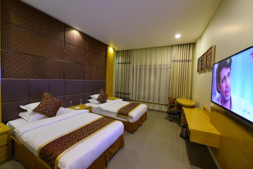 a hotel room with two beds and a flat screen tv at Hotel H - Sandhill Hotels Private Limited in Anand