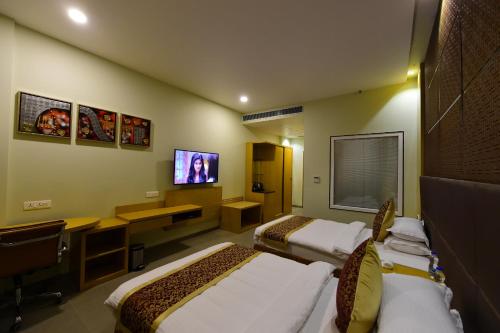 a hotel room with two beds and a tv at Hotel H - Sandhill Hotels Private Limited in Anand