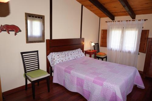 a bedroom with a bed and two chairs and a window at Casa del Pinar in Enciso