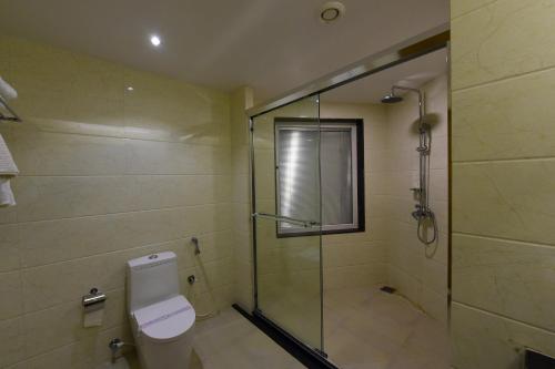 a bathroom with a glass shower and a toilet at Hotel H - Sandhill Hotels Private Limited in Anand