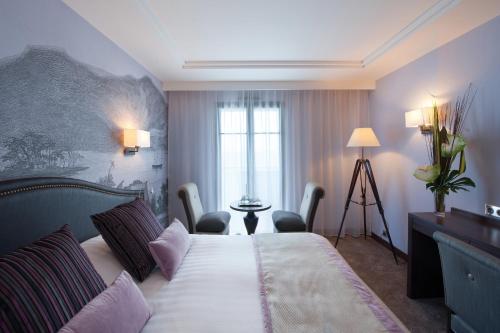 a hotel room with a bed with chairs and a window at Hôtel Le Nouveau Monde in Saint Malo