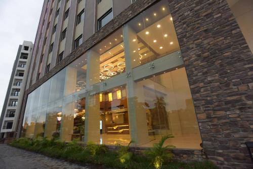 a large building with glass windows on a street at Hotel H - Sandhill Hotels Private Limited in Anand