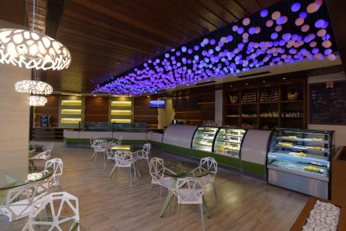 a restaurant with white chairs and tables and purple lights at Hotel H - Sandhill Hotels Private Limited in Anand