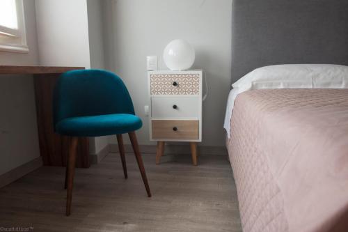 a bedroom with a blue chair next to a bed at Dimora 16 Rooms & Garden in Prato