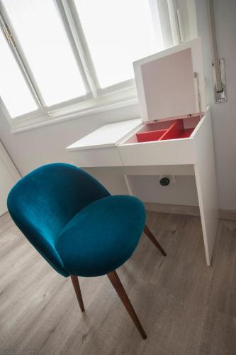 a blue chair sitting in front of a desk at Dimora 16 Rooms & Garden in Prato