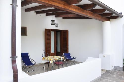 eine Terrasse mit Stühlen und einem Tisch an einer weißen Wand in der Unterkunft Case Vacanze S. Anna in Lipari