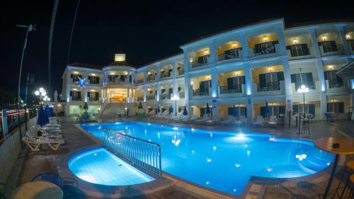 a large swimming pool in front of a building at night at Aphrodite Hotel in Laganas