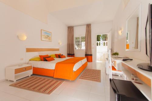 een slaapkamer met een oranje bed en een bureau bij El Mouradi Club Kantaoui in Port El Kantaoui