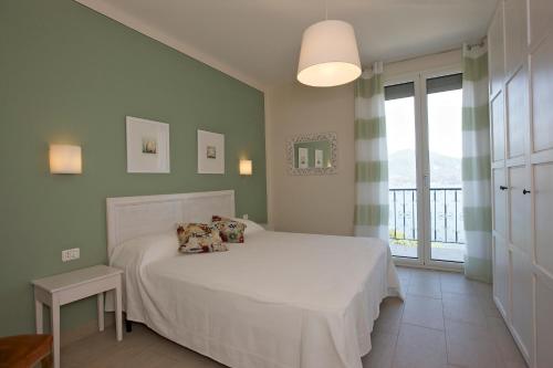 a bedroom with a white bed and a large window at Casa Balon in Oggebbio