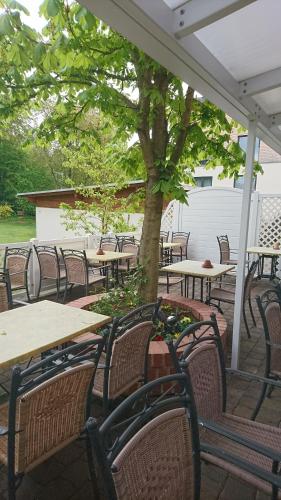 an outdoor patio with tables and chairs and a tree at Hotel & Auberge le Journal in Sankt Wendel