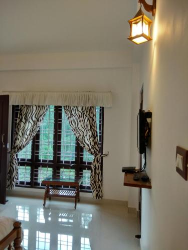 a room with a window with a bench and a television at Aditi in Thekkady