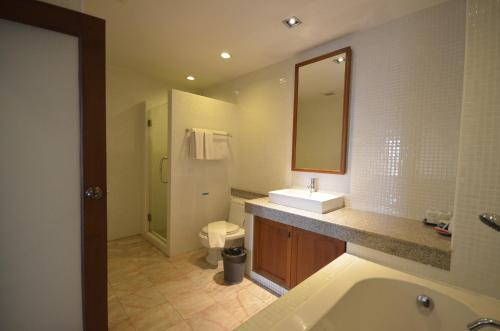 een badkamer met een wastafel, een toilet en een spiegel bij Sakorn Residence and Hotel in Chiang Mai