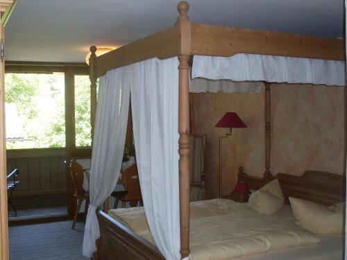 a bedroom with a canopy bed with a white curtain at Gasthof Ochsenwirt in Oberaudorf