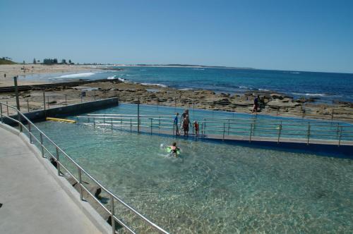 a group of people in the water at a beach at Jetty Motel The Entrance in The Entrance