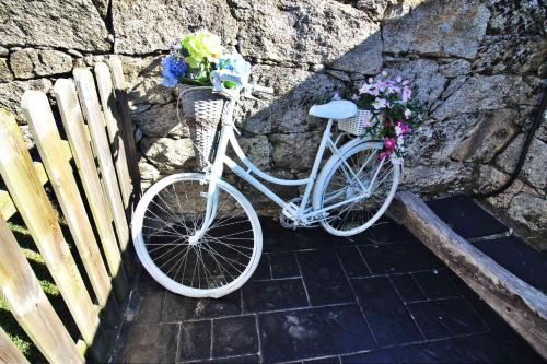 a white bike parked next to a stone wall with flowers at Apartadiño in Pobra do Caramiñal